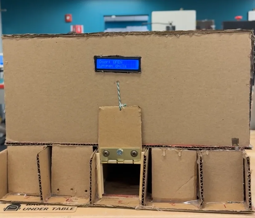 Cardboard prototype of the box with an LCD and servo-pulled doors above five open compartments